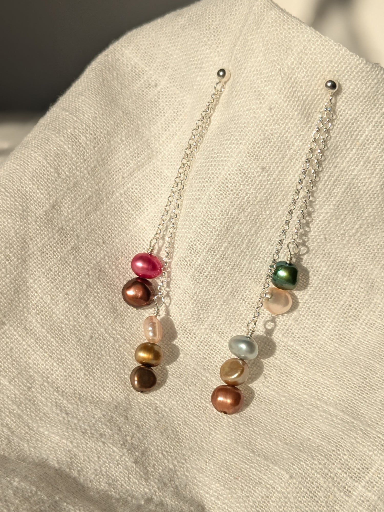 multi colour pearl drop stud earrings on linen