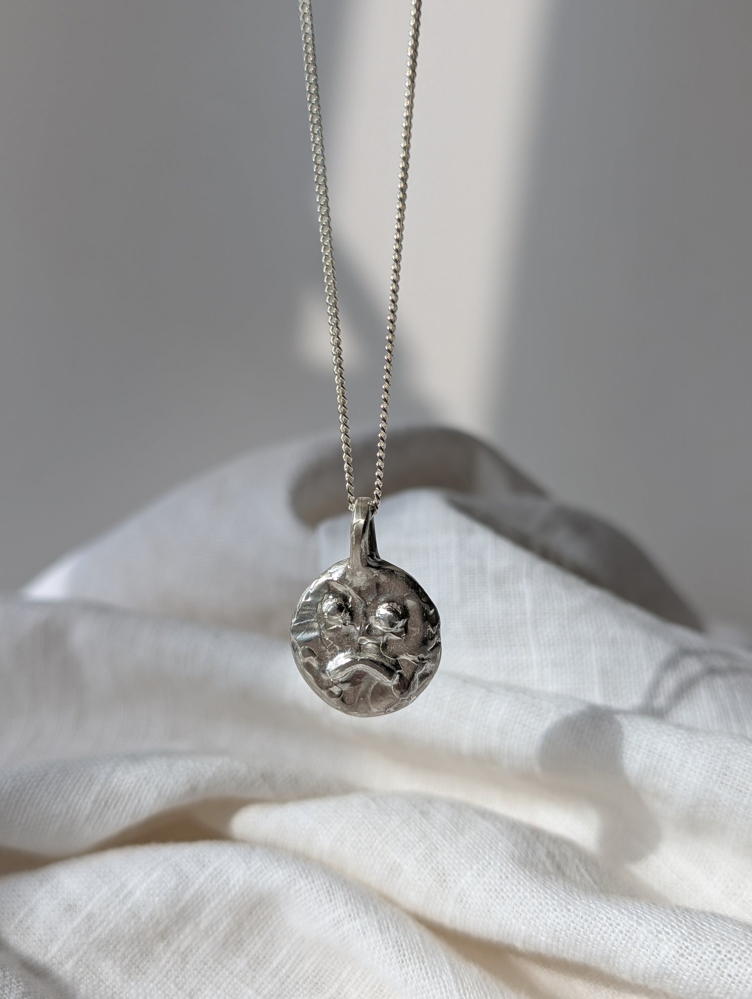 Silver Sasta Smily irish jewellery necklace with a decorative pendant on a white fabric background