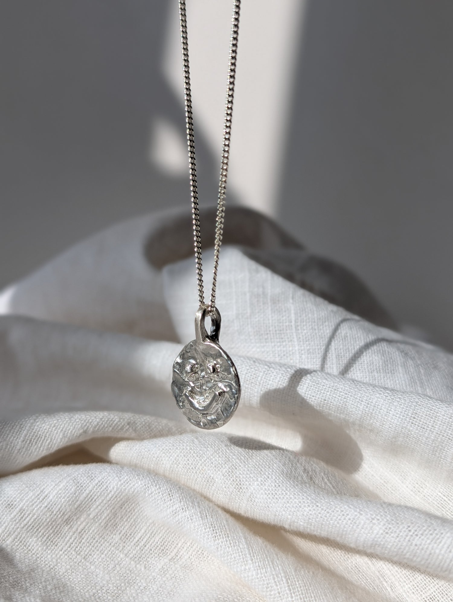 Silver Smilet necklace with a pendant on a white fabric background