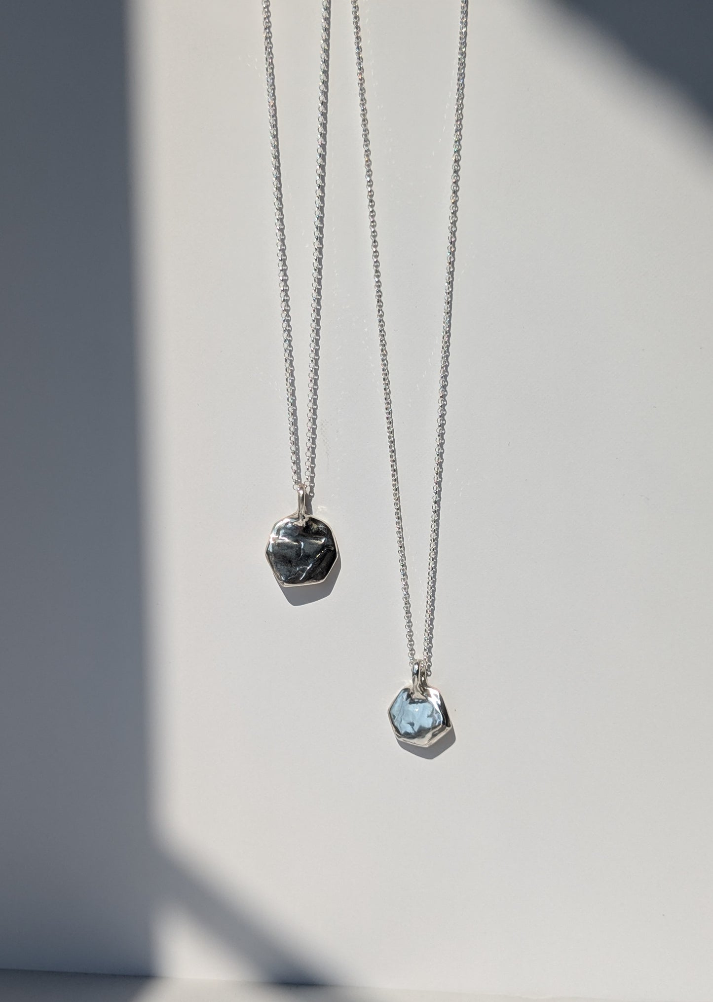 Two silver necklaces with pendant stones on a light gray background, giants causeway irish jewellery