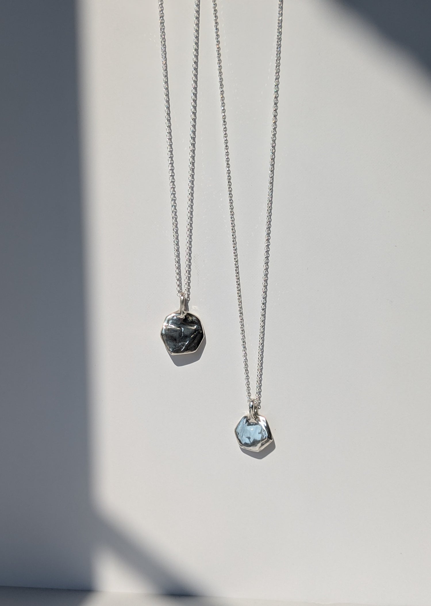 Two silver necklaces with pendant stones on a light gray background, giants causeway irish jewellery