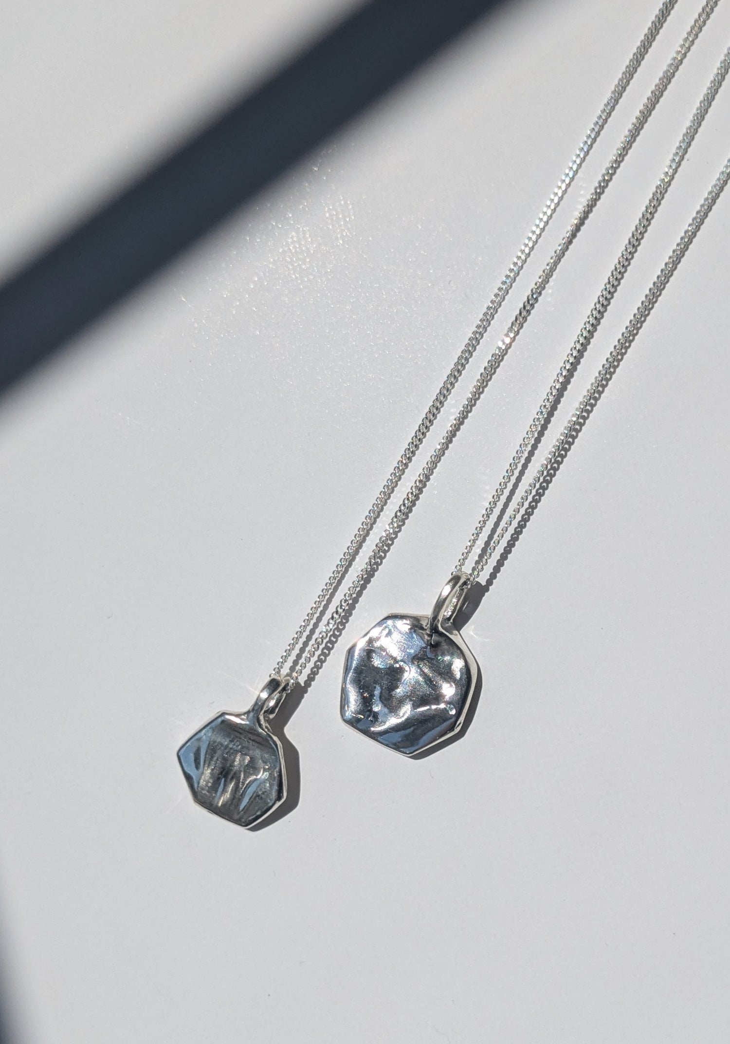 Two silver necklaces with pendant stones on a light gray background, giants causeway irish jewellery