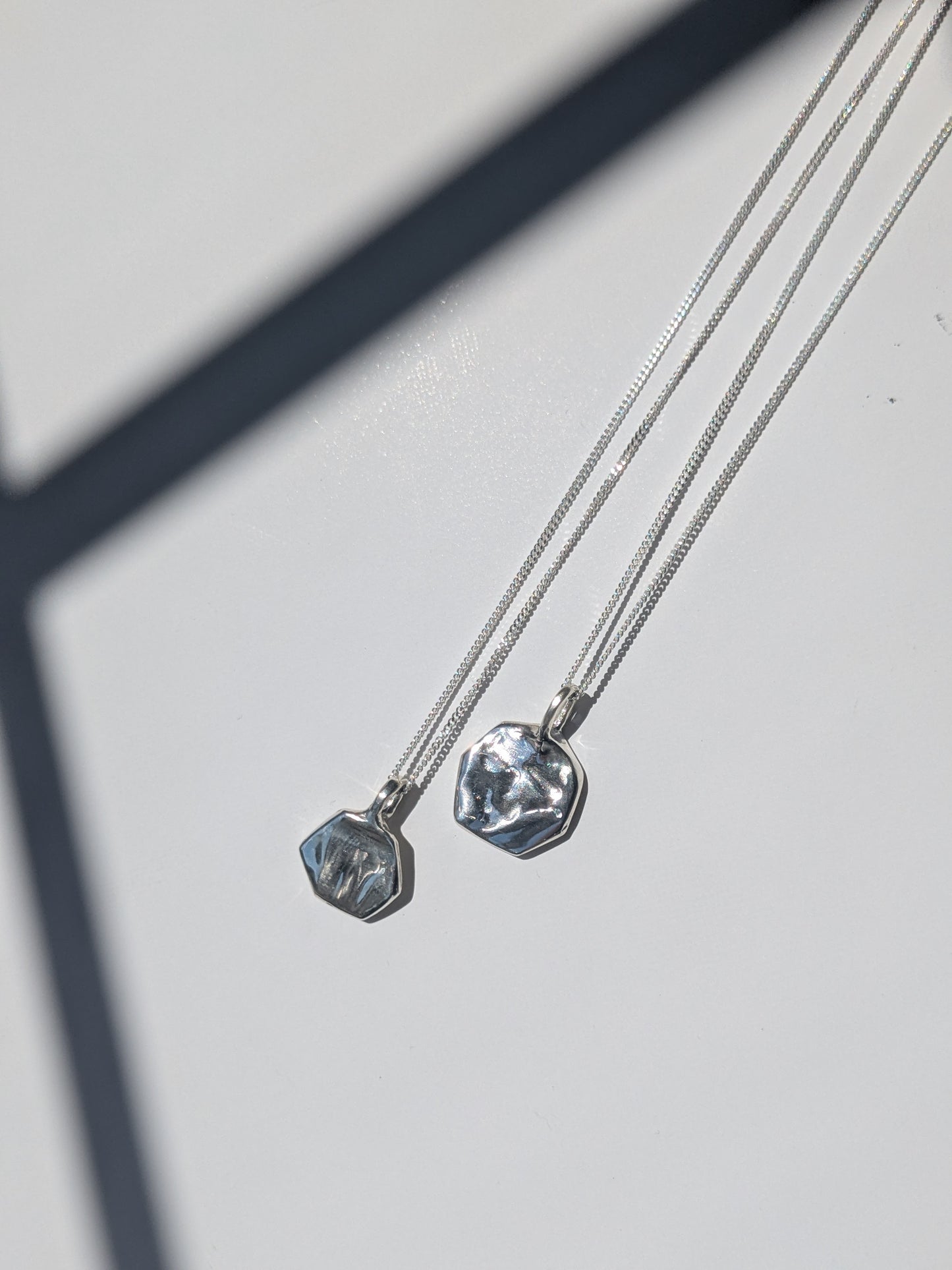 Two silver necklaces with pendant stones on a light gray background, giants causeway irish jewellery
