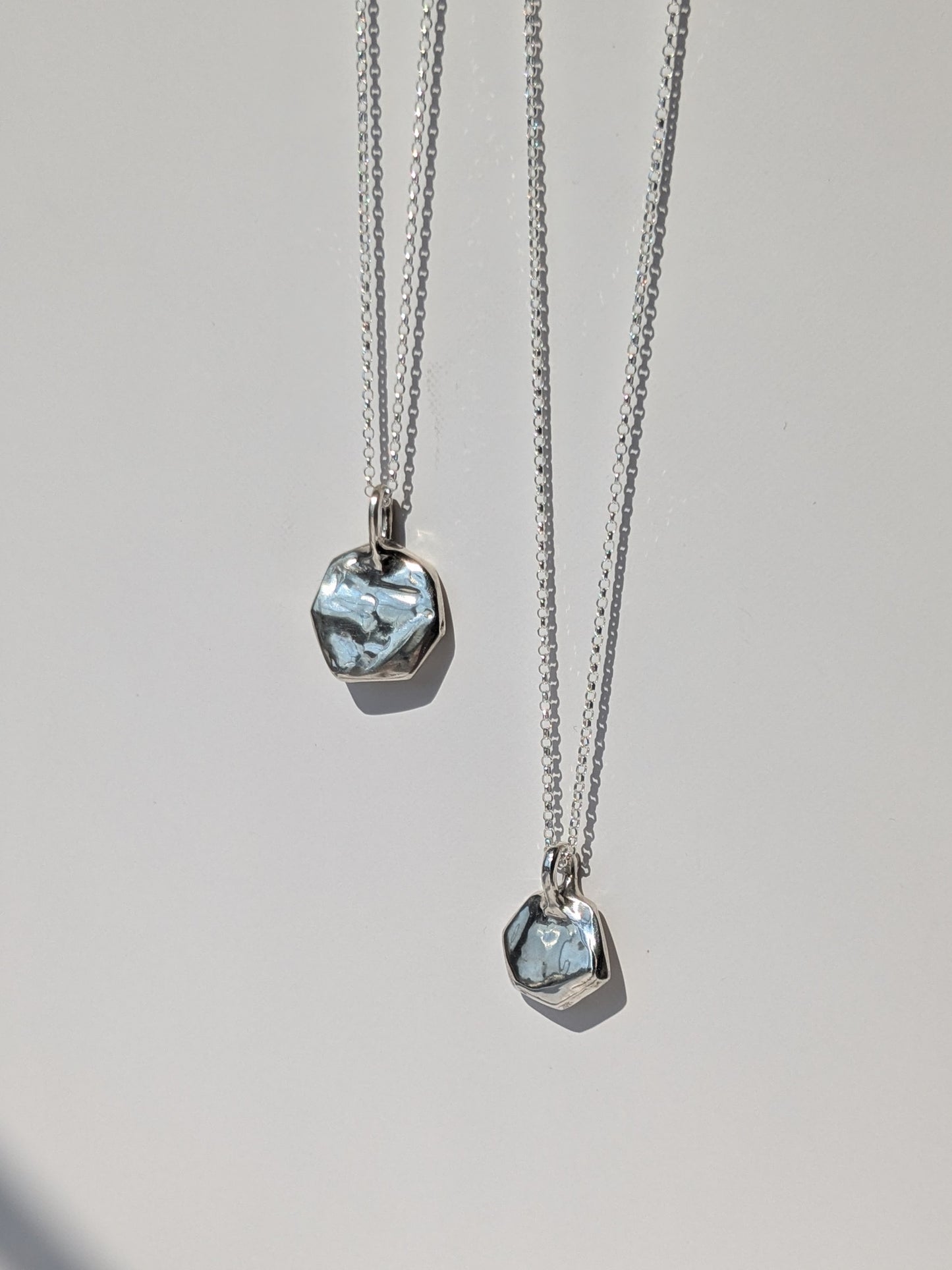 Two silver necklaces with pendant stones on a light gray background, giants causeway irish jewellery