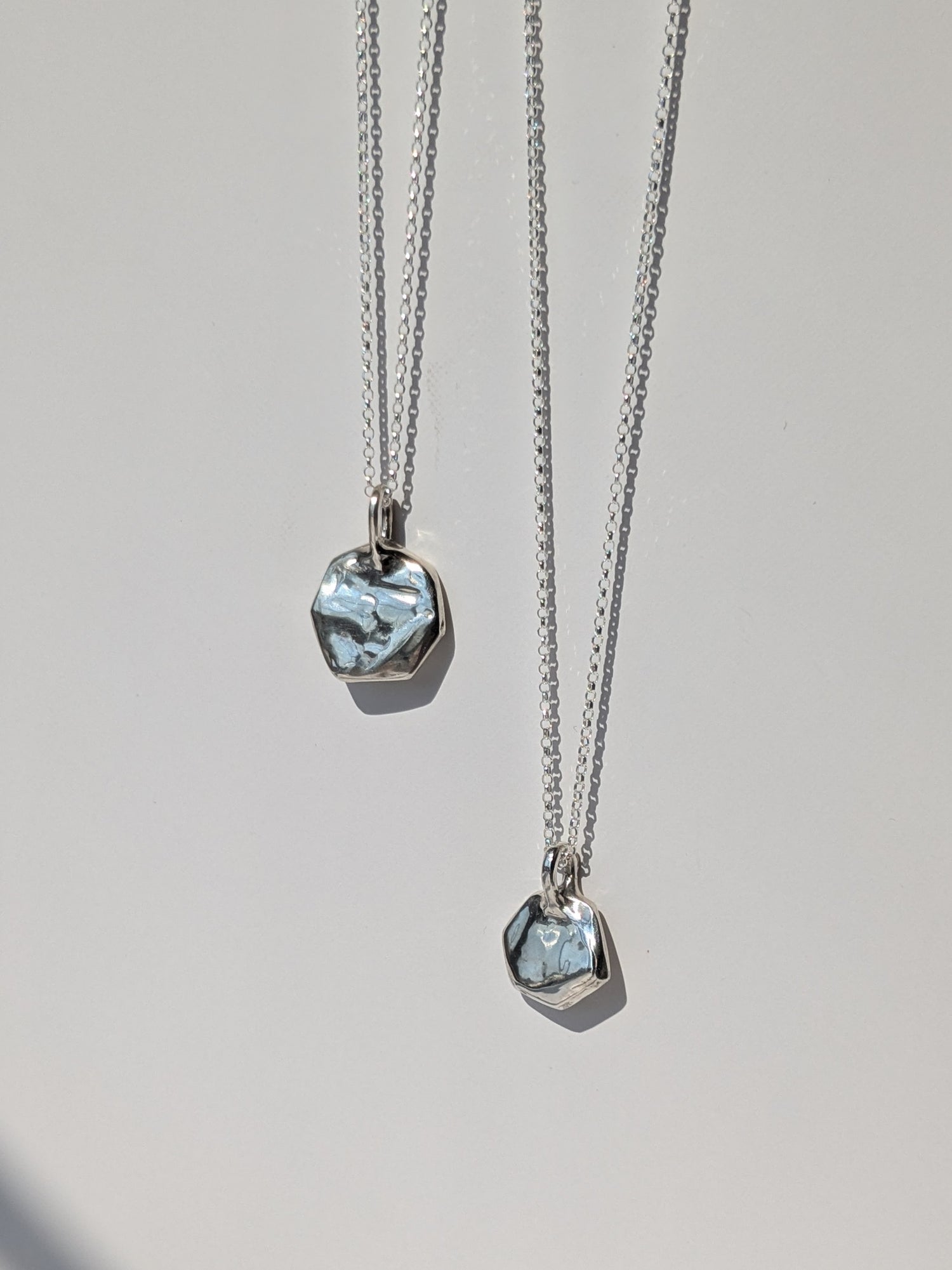 Two silver necklaces with pendant stones on a light gray background, giants causeway irish jewellery