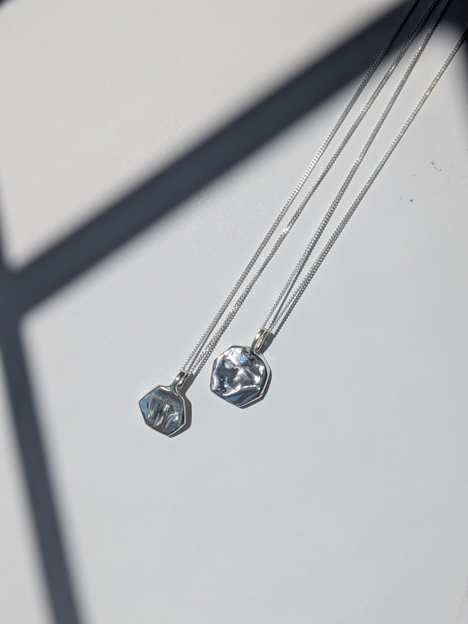 Two silver necklaces with pendant stones on a light gray background, giants causeway irish jewellery