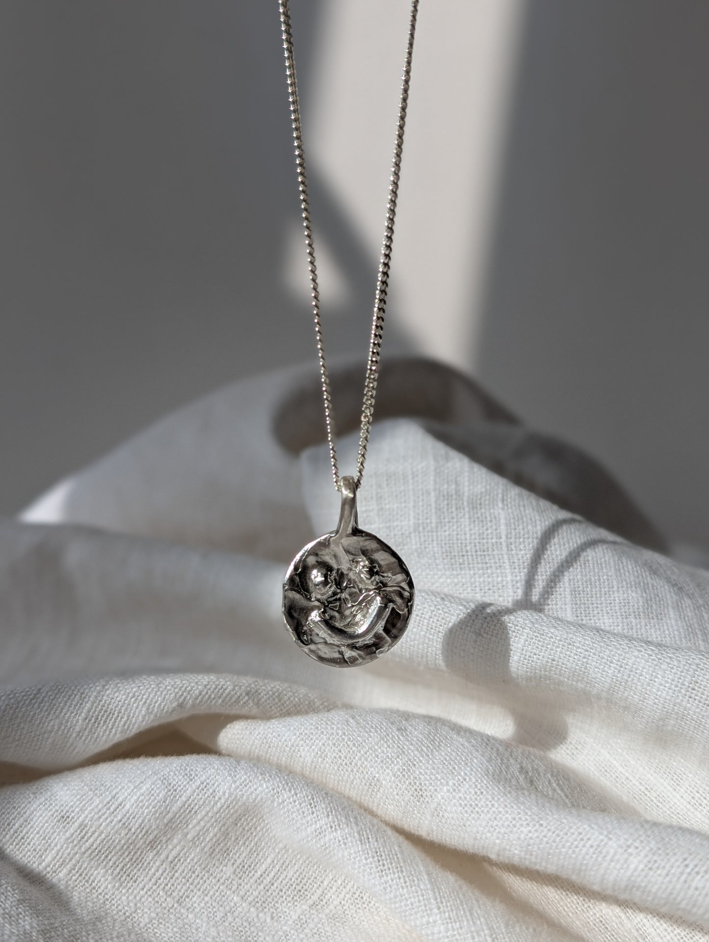 Silver smiley Irish necklace with a pendant on a white fabric background