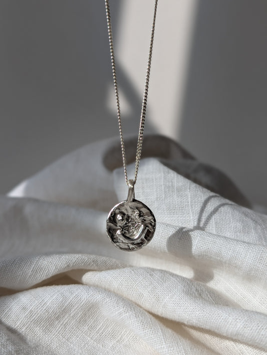 Silver smiley Irish necklace with a pendant on a white fabric background